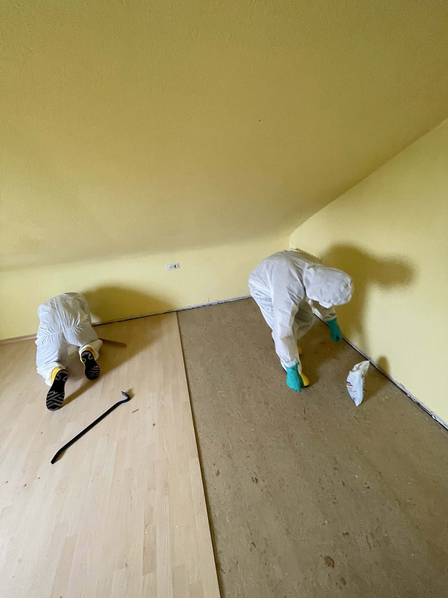 Zwei Mitarbeiter in Schutzkleidung beim Entfernen von Laminat