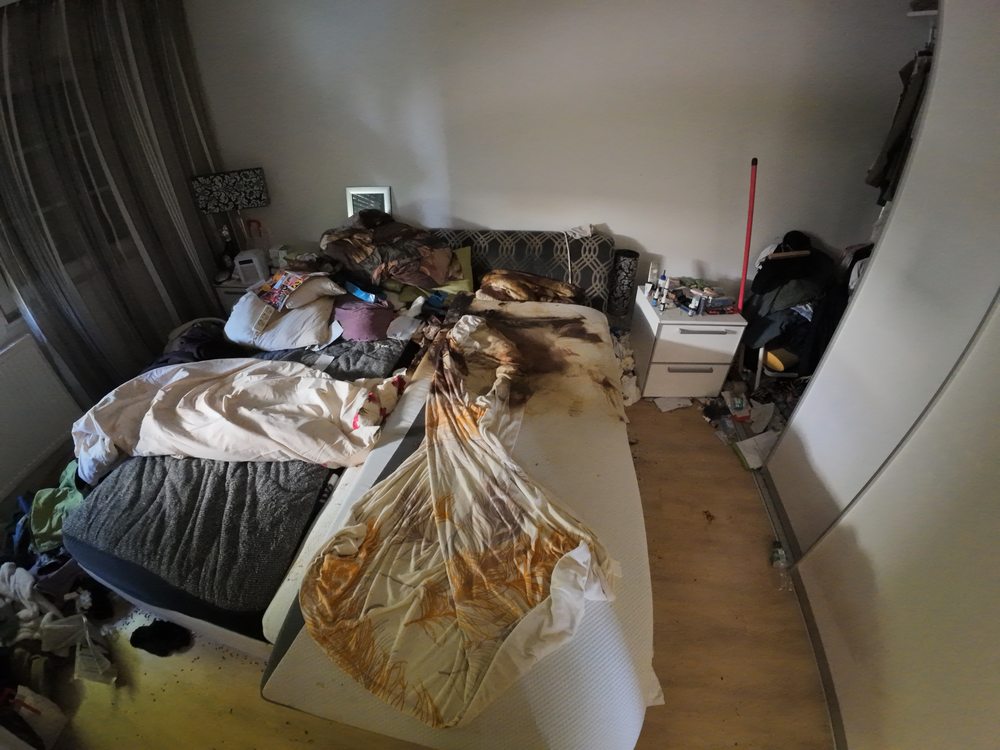 Schlafzimmer mit Bett, Textilien und biologischen Rückständen