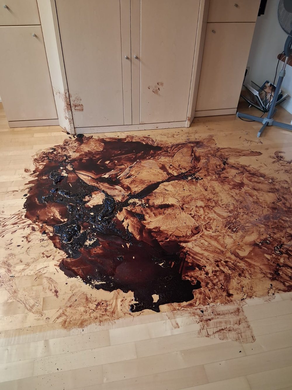 Holzboden mit großflächigen Blutspuren vor einem Schrank