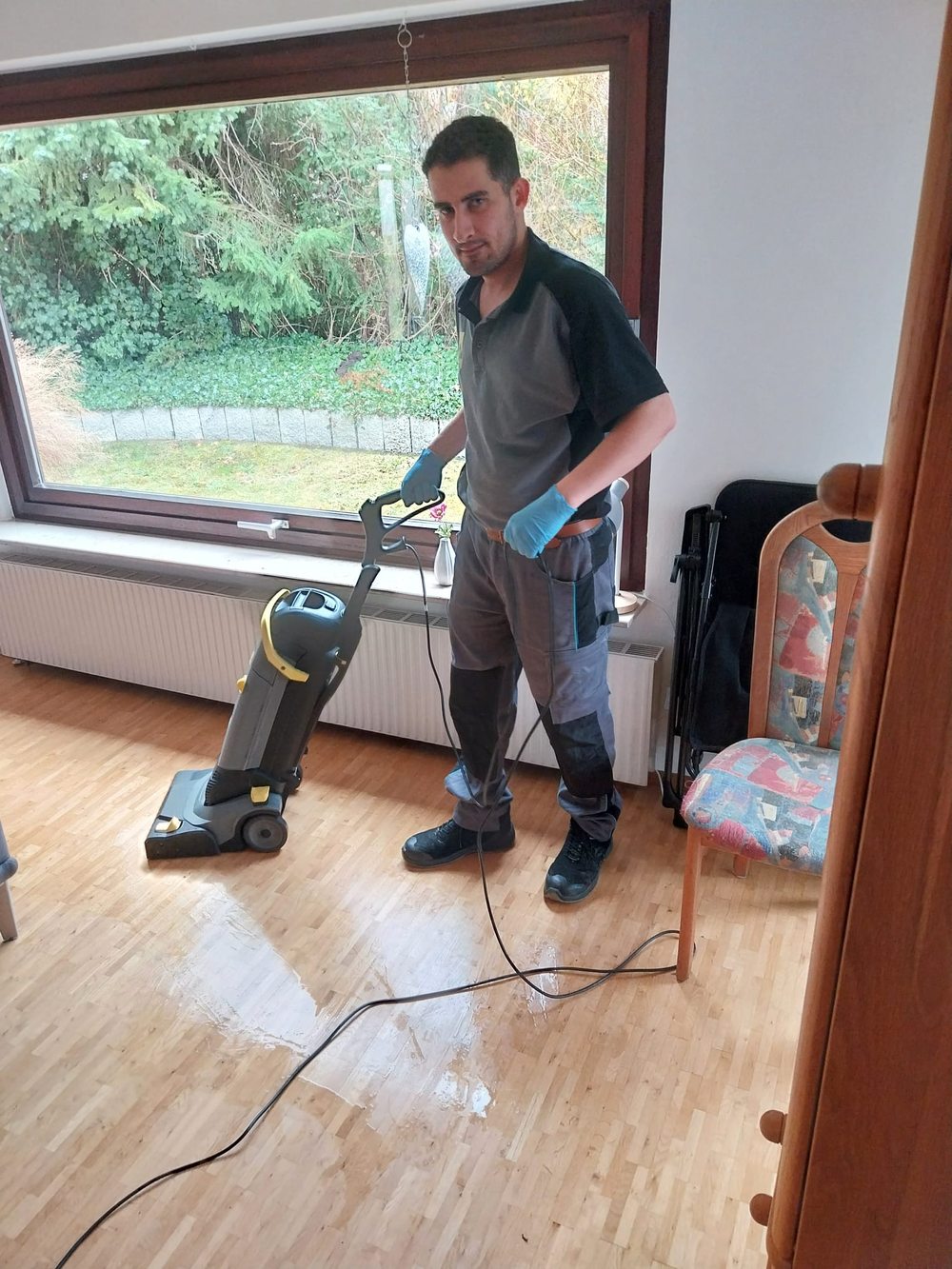 Mitarbeiter mit einer Scheuersaugmaschine in einem hellen Raum